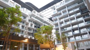 Een meerlaags gebouw met balkons, grote ramen en bomen in de binnentuin.
