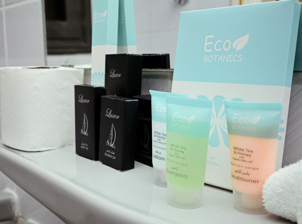 A shelf with various Eco Botanics products including a shower cap, lotion, shampoo, and conditioner.