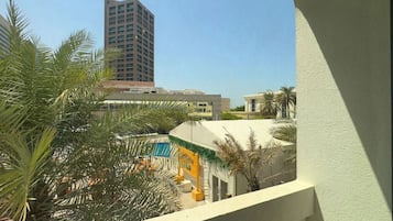 Enjoy a serene view from this balcony overlooking the surrounding complex, surrounded by palm trees and a clear blue sky.