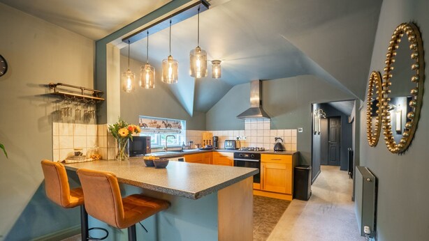 A modern kitchen with a central island, pendant lighting, and a decorative mirror.