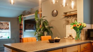 A kitchen with a granite countertop, a clock, a plant, and a vase with flowers.