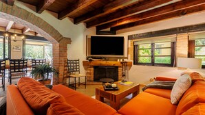Una sala de estar acogedora con chimenea, sofás anaranjados y un televisor montado en la pared.