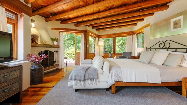 Ein gemütliches Schlafzimmer mit Holzboden, einem großen Bett, einem Fernseher und einem Kamin.