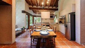 A spacious kitchen with a large wooden table set for dining, equipped with modern appliances and a view to the outside. - Casa Abi - Garden and River Retreat (Valle de Bravo)