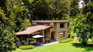 A modern house with a patio, surrounded by lush greenery. - Casa Abi - Garden and River Retreat (Valle de Bravo)