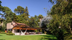 A modern house with a covered patio, a stone staircase, and a well-maintained lawn. - Casas Abi: A Riverside Sanctuary with Firepit in Avándaro (Valle de Bravo)