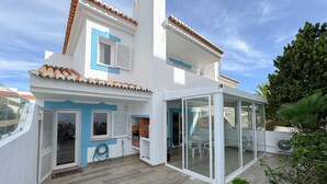 Ein modernes, zweistöckiges Haus mit Terrasse und Wintergarten, dazu eine Wand in Blau.