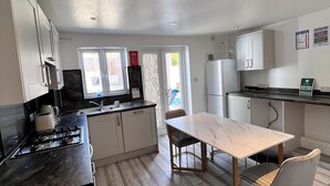 A modern kitchen with a dining area, featuring a stove, sink, and cabinets. - Gillingham - 3 Beds - Sleeps 6 - Garden - Wifi (Gillingham)