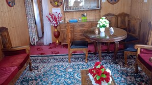 Una habitación tradicional con detalles de madera, una mesa redonda con sillas, un espejo y una alfombra estampada.