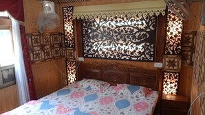 Una habitación de madera con una cama, un ventilador de pared y paneles decorativos.
