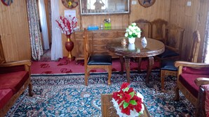 Una habitación tradicional con decoración de madera, una mesa redonda con sillas, un aparador de madera y un espejo en la pared.
