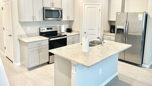 A modern kitchen with white cabinets, stainless steel appliances, and a granite countertop. - Comfortable 3-Bedroom Home – Sleeps 7 – Perfect for Vacation in Nokomis, FL (Nokomis)