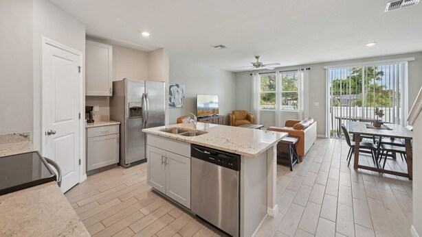 A modern kitchen with a dishwasher, refrigerator, and a dining area with a table and chairs. - Comfortable 3-Bedroom Home – Sleeps 7 – Perfect for Vacation in Nokomis, FL (Nokomis)
