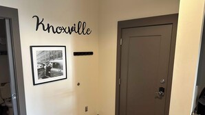 Un corridoio con una porta, un quadro incorniciato e un cartello appeso al muro con la scritta "Knoxville".