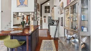 A modern kitchen with a central island, stainless steel appliances, and a variety of decorative items on the walls. - Chic Loft Retreat blocks from the Quarter! (New Orleans)