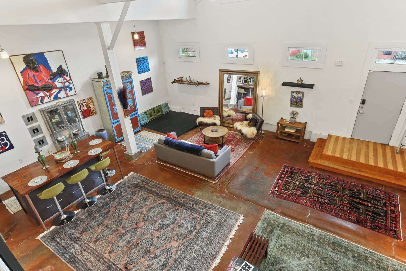 A spacious living area with a large sofa, a dining table, and multiple rugs.