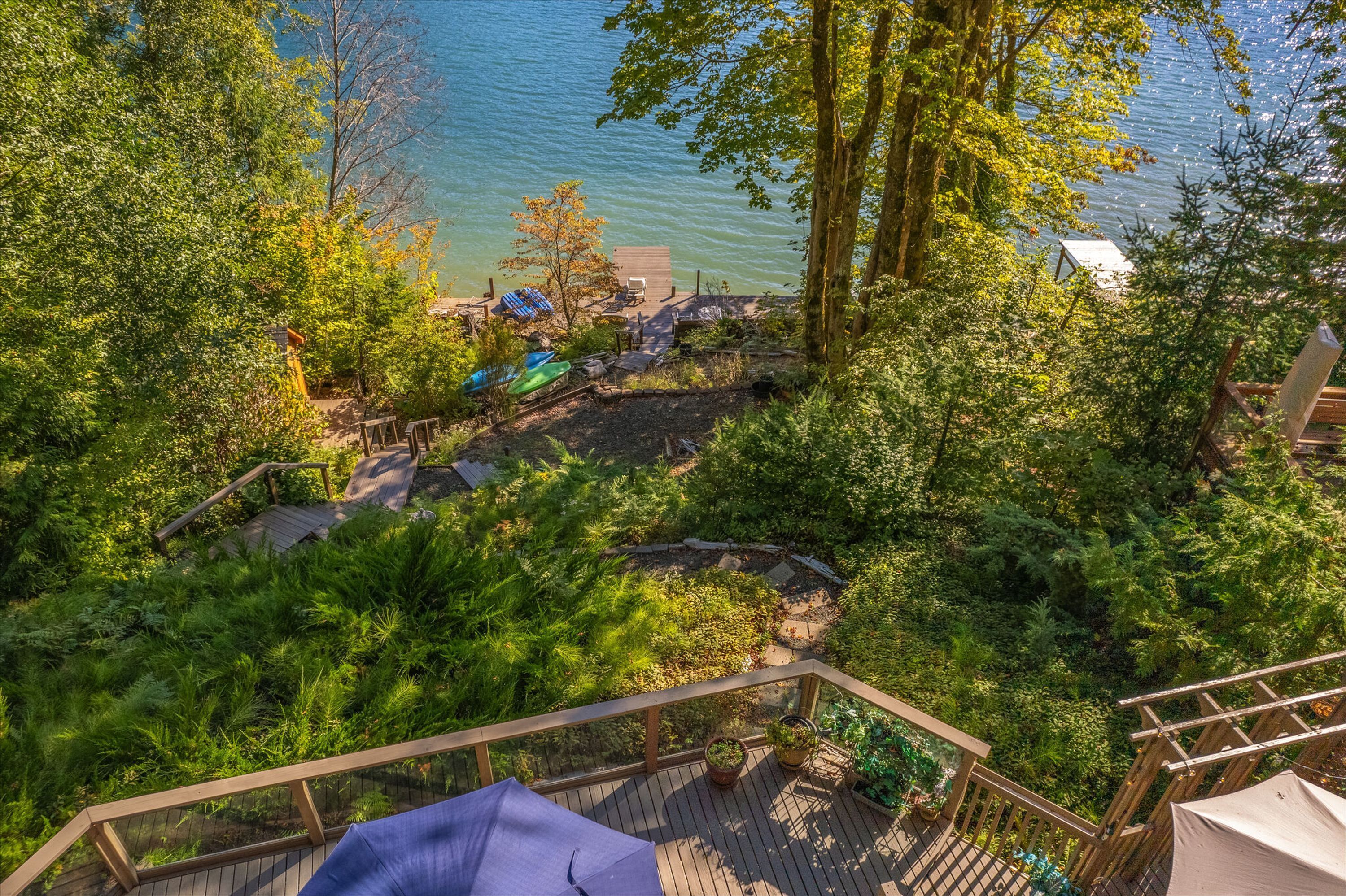 Eine Terrasse mit Blick auf einen See, umgeben von dichter Vegetation und einigen Strandsonnenschirmen.