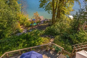 Eine Terrasse mit Blick auf einen See, umgeben von dichter Vegetation und einigen Strandsonnenschirmen.