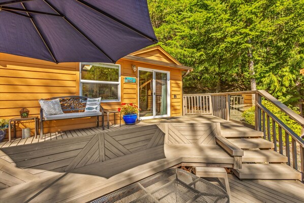 A wooden deck with a bench, a potted plant, and a large umbrella.