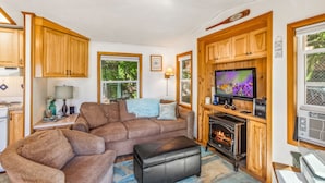 A cozy living room with a fireplace, wooden cabinets, a television, and a comfortable sofa. - Reed s Cove Cabin in Hoodsport (Hoodsport)