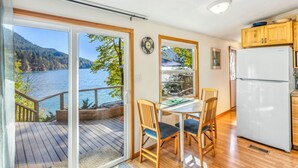 A kitchen with a view of a lake, wooden cabinets, and a white refrigerator. - Reed s Cove Cabin in Hoodsport (Hoodsport)