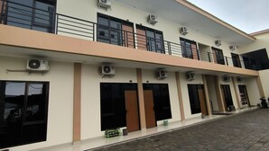 A building with multiple air conditioning units, large windows, and a paved entrance area.