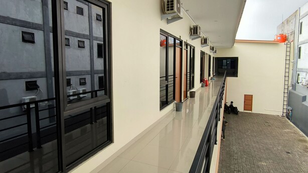 A corridor with large windows, air conditioning units, and a tiled floor.