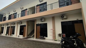 A multi-story building with air conditioning units, a staircase, and a motorcycle parked outside.