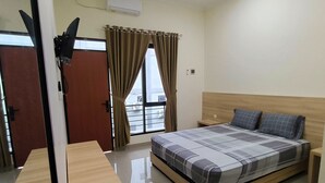 A hotel room with a bed, bedside table, and a window with curtains.
