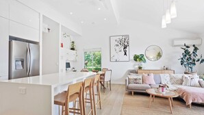 Cozinha moderna com armários brancos, eletrodomésticos de aço inoxidável e uma ilha central com banquetas.