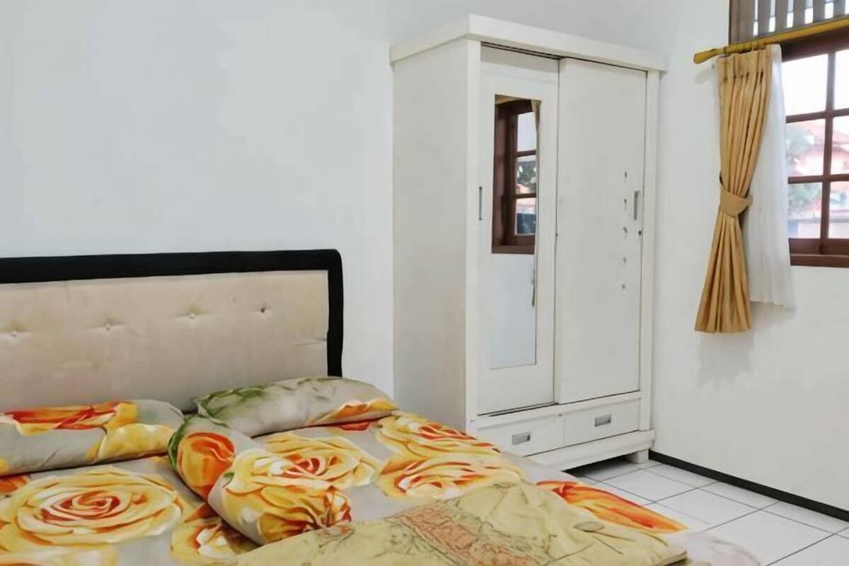 Un dormitorio con cama, armario y ventana con cortinas.