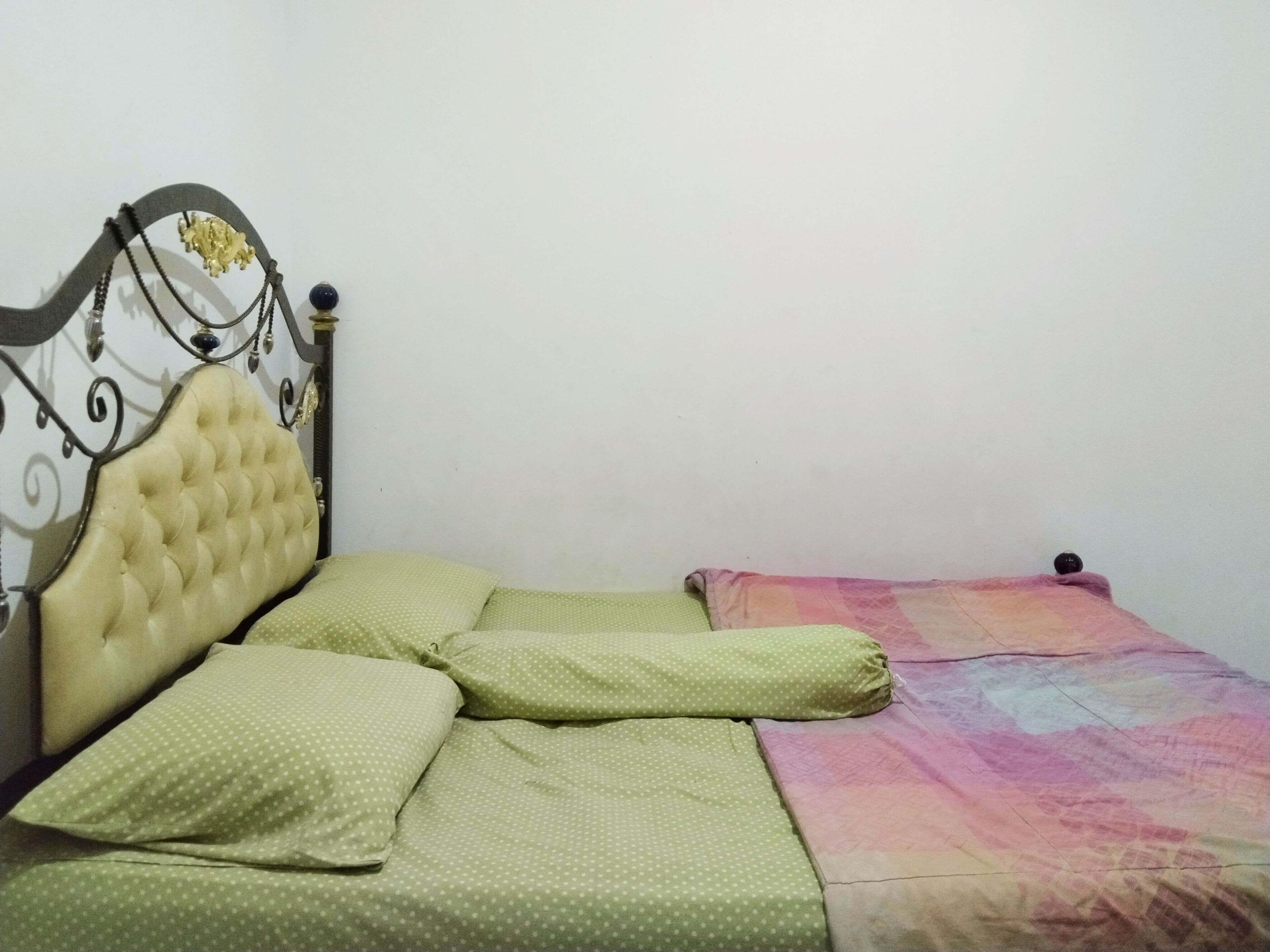 A bed with a tufted headboard and green polka dot bedding.