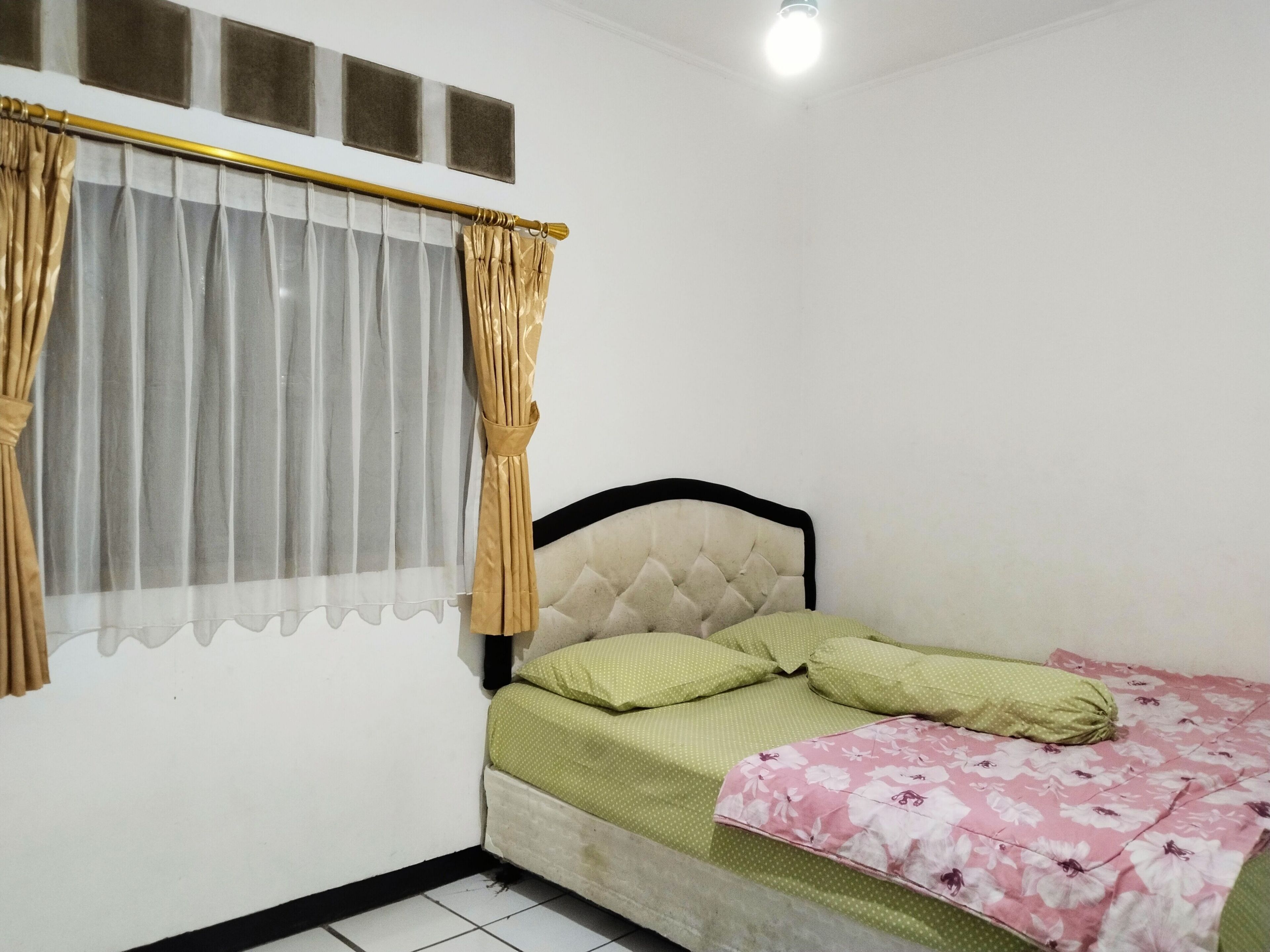 A small, simple bedroom with a bed, curtains, and a window.