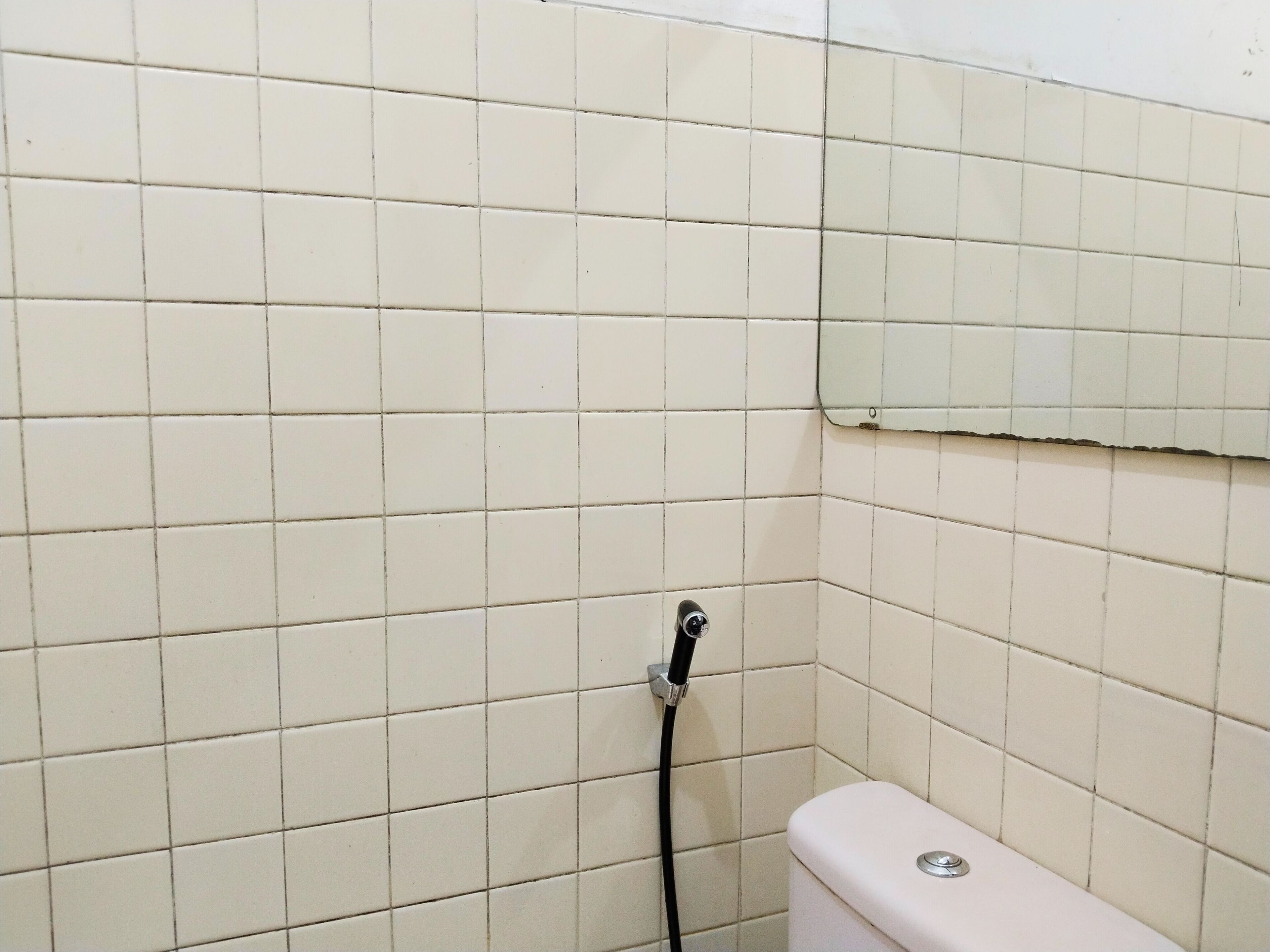 Ein Badezimmer mit weiß gefliesten Wänden und einer weißen Toilette.