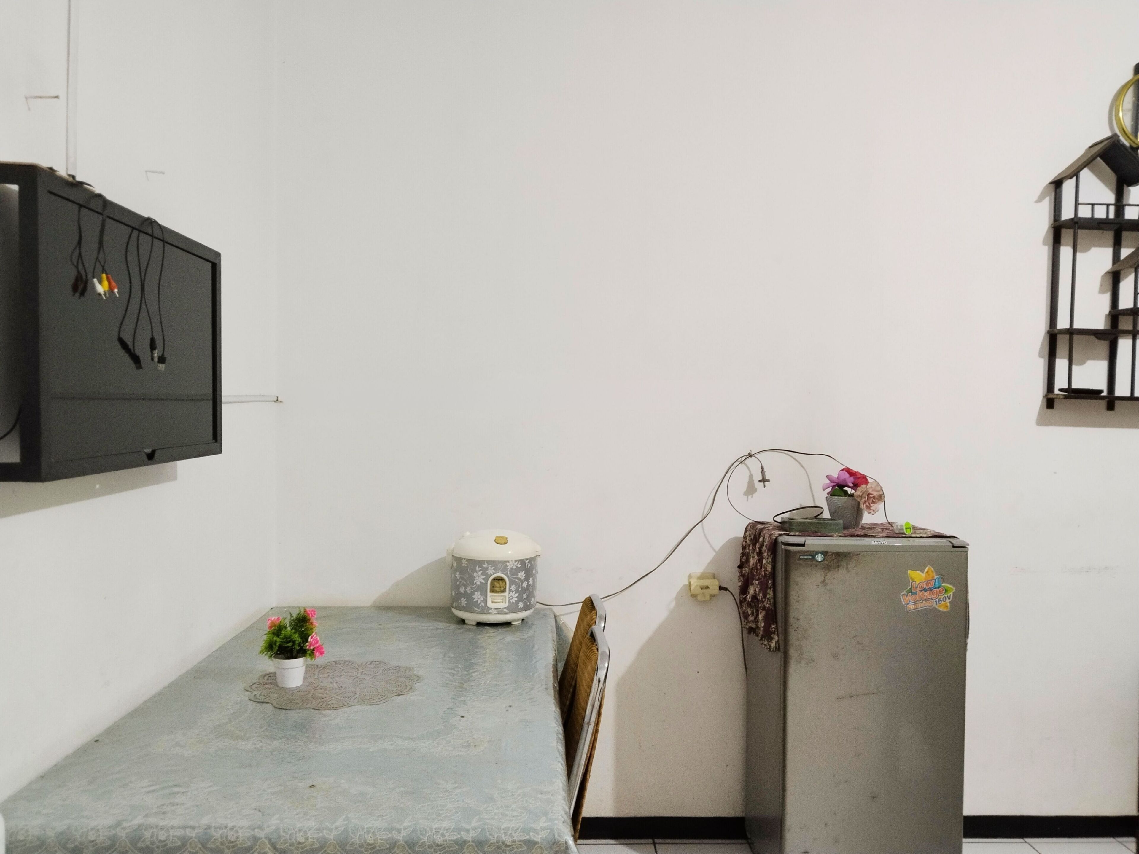 A small kitchen with a refrigerator, a microwave, and a small table with a potted plant.
