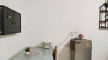A small kitchen with a refrigerator, a microwave, and a small table with a potted plant.