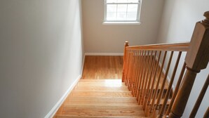 Eine Holztreppe mit weißer Wand und einem Fenster oben.