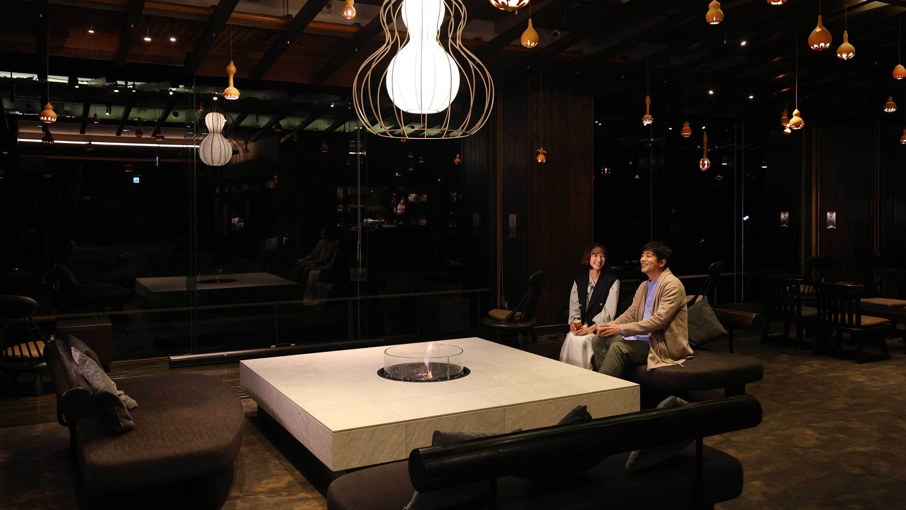 Un intérieur moderne avec une table centrale, des sièges et des suspensions lumineuses.