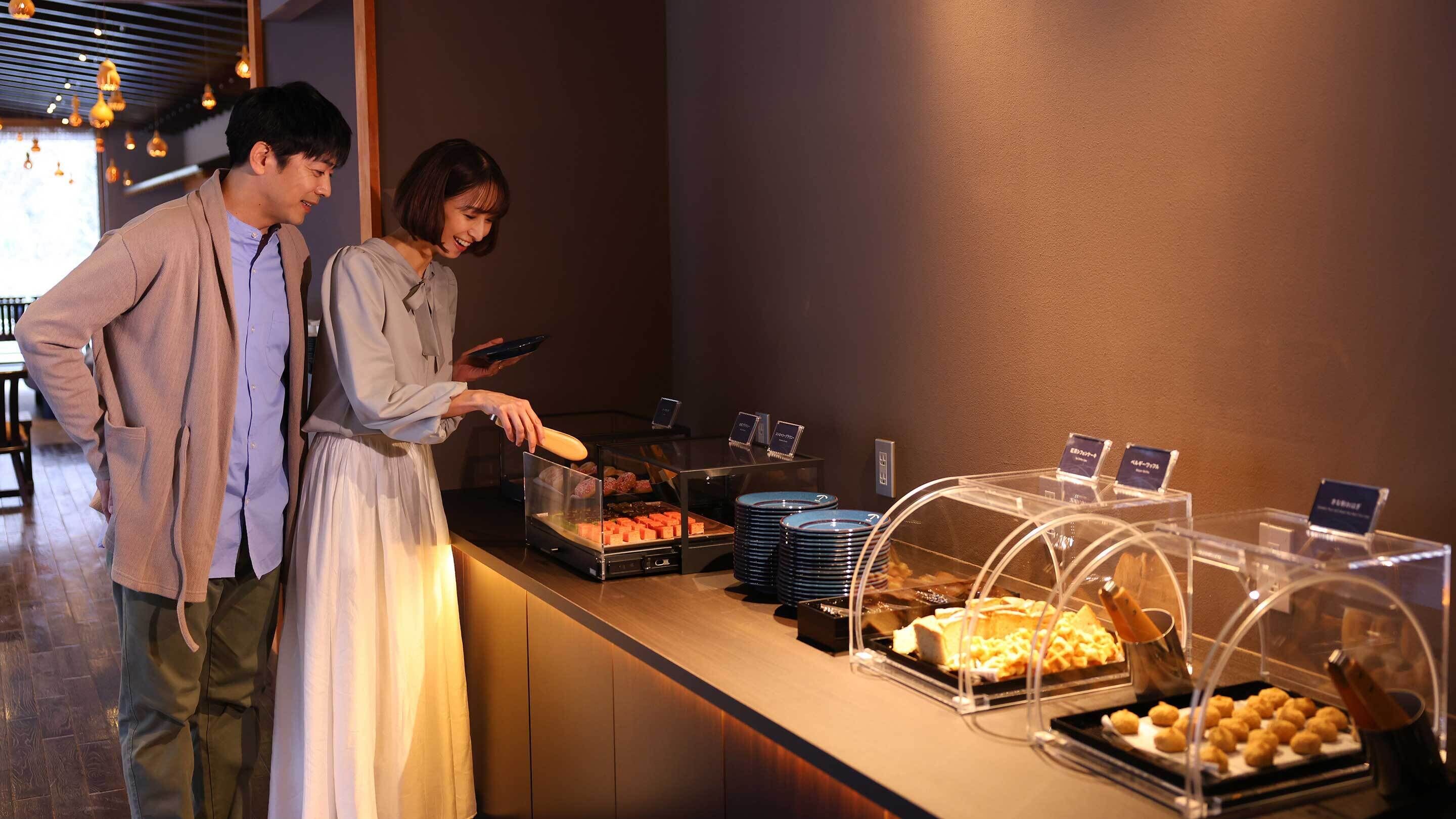 A buffet area with various food items and a digital menu board.