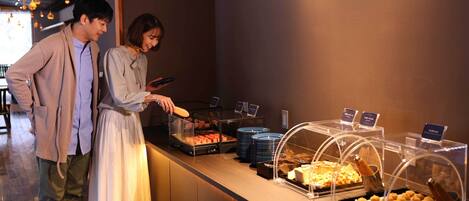 A buffet area with various food items and a digital menu board.