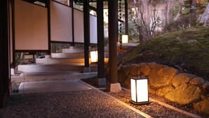 Un bâtiment de style japonais traditionnel, avec un chemin de pierre menant à une entrée en bois.