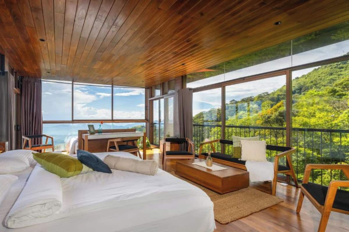 A spacious bedroom with a large bed, a desk, and a balcony with a scenic view.