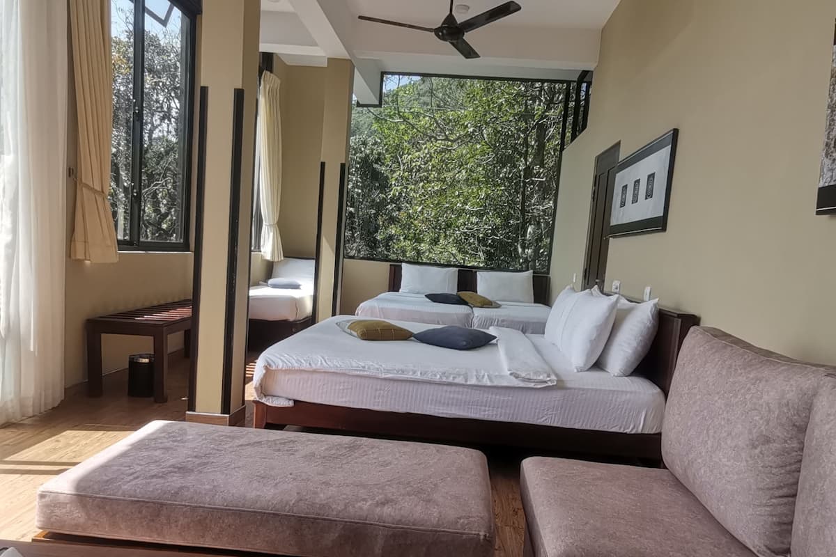 A room with two beds, a sofa, a small table, and a ceiling fan.