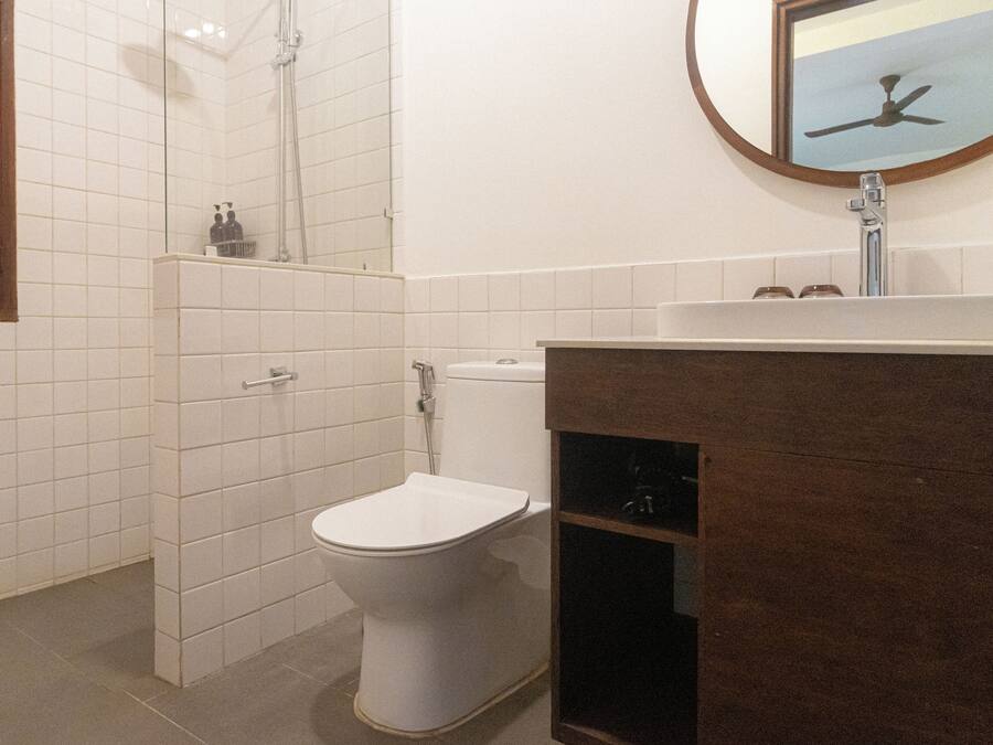 Une salle de bain équipée de toilettes, d’une douche et d’un lavabo avec un miroir au-dessus.