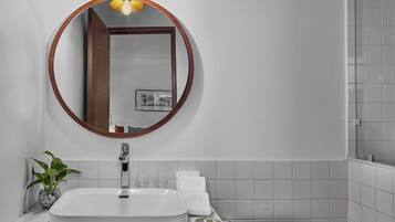 Un baño con un espejo redondo, un lavabo blanco y un inodoro.