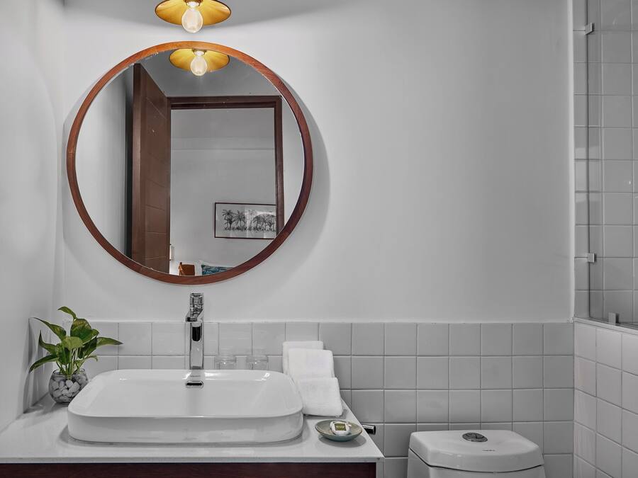 Un baño con un espejo redondo, un lavabo blanco y un inodoro.