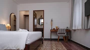 A hotel room with a bed, a desk, a mirror, and a TV.
