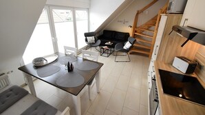 Un appartement moderne de style « loft » comprenant un coin repas, une cuisine et un escalier menant à un niveau supérieur.