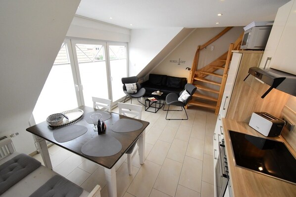 Un appartement moderne de style « loft » comprenant un coin repas, une cuisine et un escalier menant à un niveau supérieur.