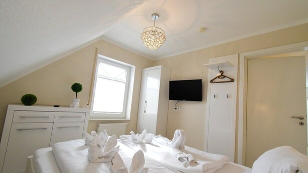 Une chambre d’hôtel avec un lit, une commode, une télévision et une fenêtre.